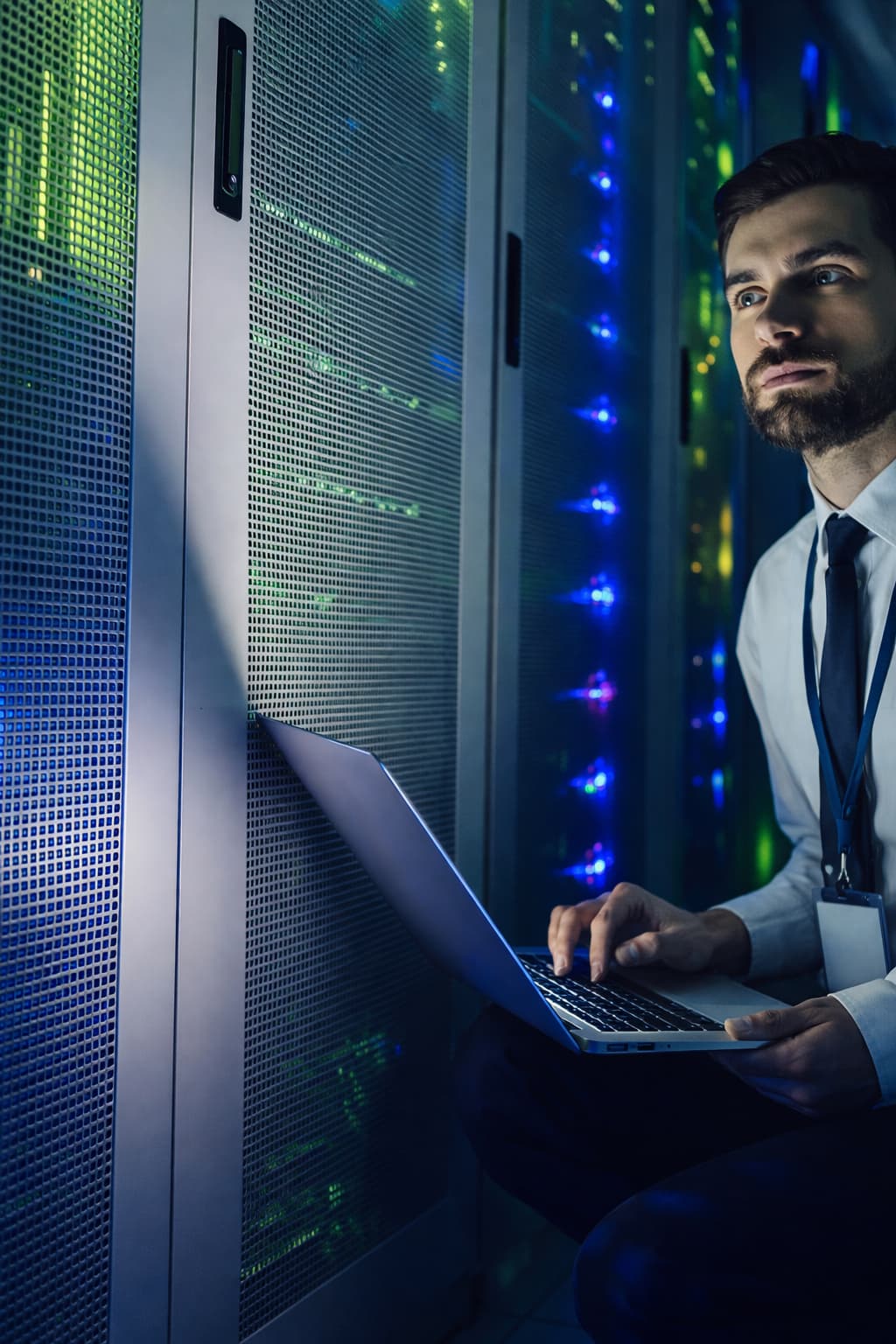 Technician using a laptop beside network equipment racks